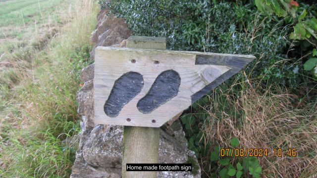 Homemade wooden footpath sign in countryside.