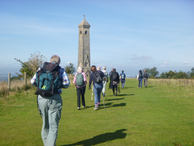 Group of hikers approaching a tall stone tower.