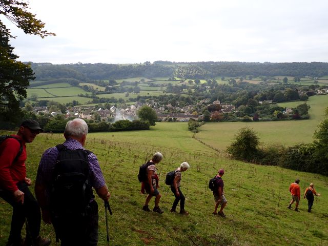 Hikers walking down a hill towards a village.