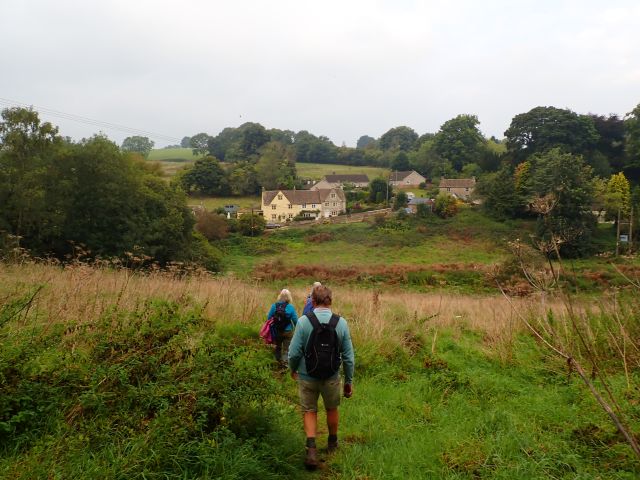 Hikers walk towards countryside village houses