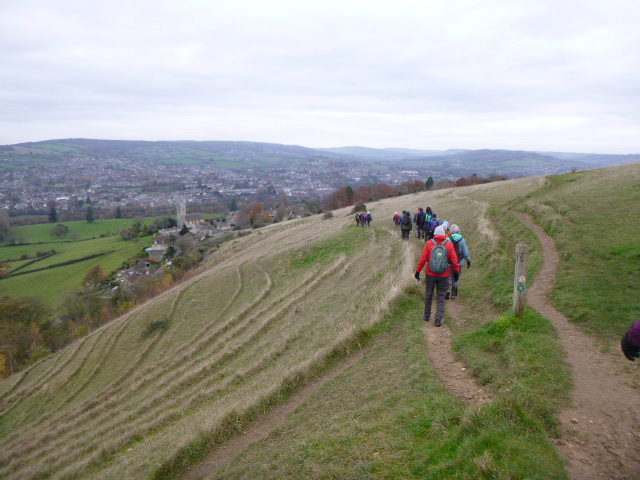 Hikers walking on hillside near scenic village view.