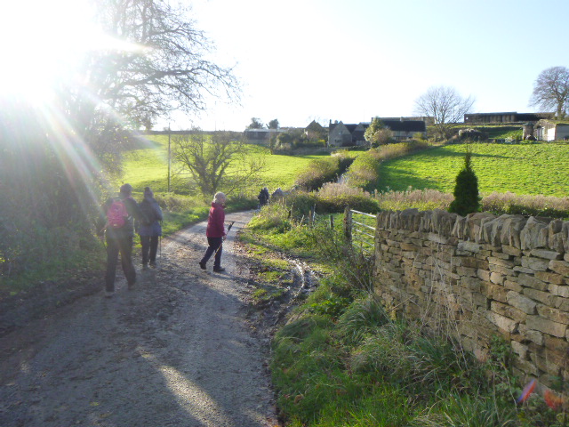 People walking on a countryside path in sunlight.