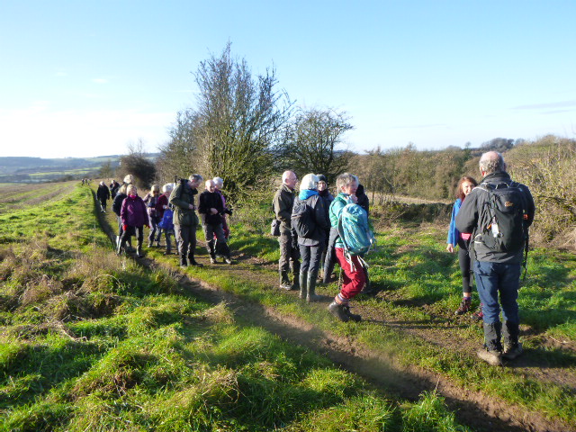 Group walking on countryside trail in winter clothing.