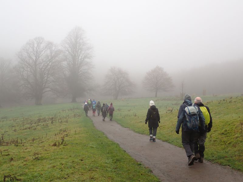 Group hiking through foggy countryside trail