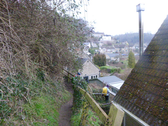 Narrow hillside path overlooking village houses and rooftops.