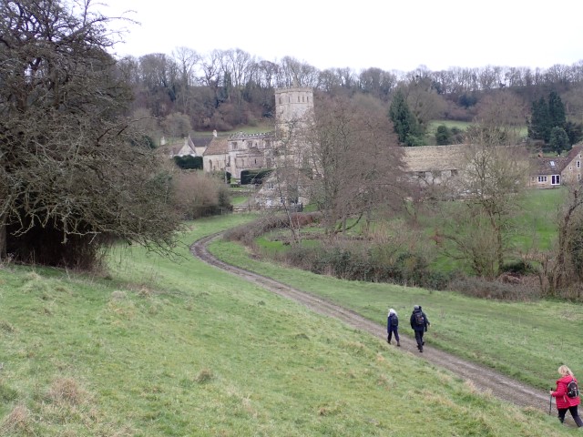 Hikers approaching English country church in rural landscape.